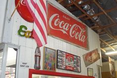 a coca - cola sign on the side of a building next to pictures and balloons