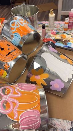 several tins with designs on them sitting on a table next to paintbrushes