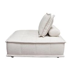 a white bed with two pillows on it and one pillow sitting on top of the mattress