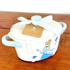 a white and blue box with a princess design on the lid sitting on top of a wooden table