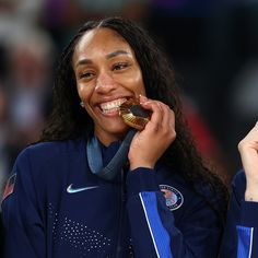 a woman with long hair is smiling while holding a medal in her hand and talking on the phone