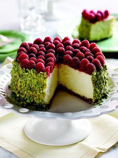 a cheesecake with raspberries on top is cut in half and sits on a plate