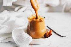 a spoon in a jar filled with caramel sauce on top of a white plate