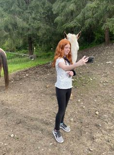 a woman taking a selfie with a horse in the background