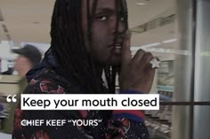 a man with dreadlocks standing in an airport talking on the phone and holding his hand to his mouth