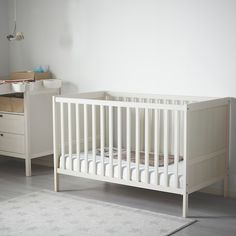 a white crib and dresser in a room