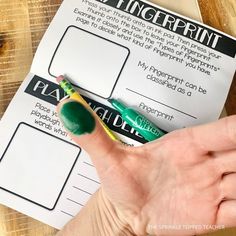 a person's hand holding a green marker next to a piece of paper