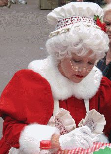 a woman dressed as santa claus is looking at her cell phone