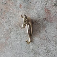 a metal horse head mounted to the side of a white wall next to a gray carpet