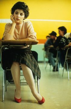 a woman sitting in a chair with her hand on her chin and looking at the camera