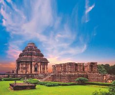 an ancient building in the middle of a lush green field under a blue sky with clouds