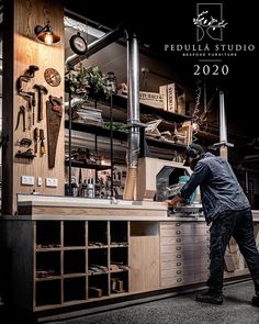 a man working in a workshop with lots of tools on the wall and shelves behind him