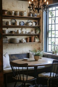 a wooden table sitting under a window next to a shelf filled with pots and pans