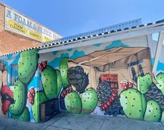 a mural painted on the side of a building in front of a cactus and pineapple