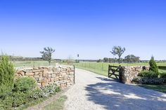 a stone wall and gate on a dirt road