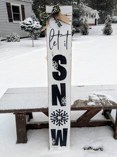 a wooden sign sitting on top of a snow covered bench