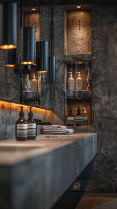 an industrial style kitchen with concrete counter tops and hanging lights over the sink area, along with several bottles on shelves