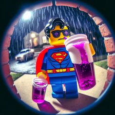 a lego man holding two cups with liquid in it and wearing a superman costume on