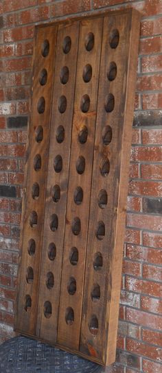 a wooden board with holes on it sitting against a brick wall in front of a chair