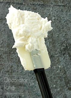 a black and white spoon with some ice cream on it's tip in front of a gray wall