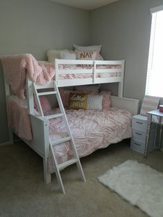 a white bunk bed sitting in a bedroom next to a desk and chair with a pillow on top of it