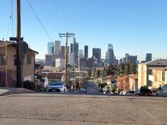 the city skyline is in the distance as cars are parked on the side of the road