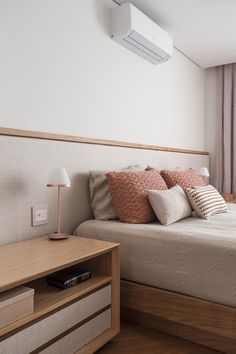 a bedroom with a bed, nightstand and air conditioner on the wall above it