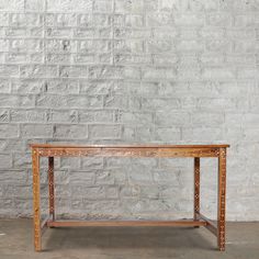 a wooden table sitting in front of a white brick wall with an iron grate on it