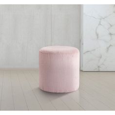 a pink stool sitting on top of a wooden floor next to a white marble wall