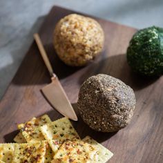 a cutting board topped with crackers, cheese balls and broccoli next to a knife