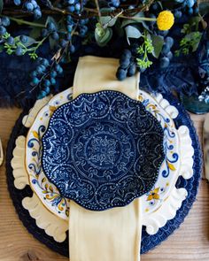 a blue and white plate sitting on top of a table next to a vase filled with flowers