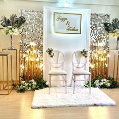 two white chairs sitting on top of a rug in front of a gold and white wall