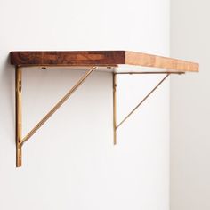 a wooden shelf sitting on top of a white wall