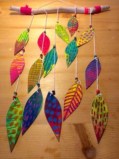 a group of colorful leaf shaped ornaments hanging from a string on top of a wooden table