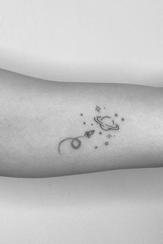 a small tattoo on the arm of a woman with an saturn and stars in it