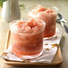 two glasses filled with ice cream sitting on top of a wooden tray