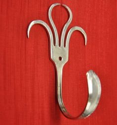 a pair of scissors hanging on the side of a red wall next to a metal hook