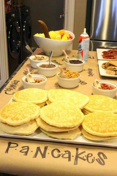 an assortment of breakfast foods on a table in front of a refrigerator and stove top