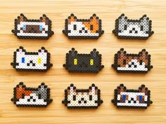 six perler beads with cats on them sitting on top of a wooden table next to each other