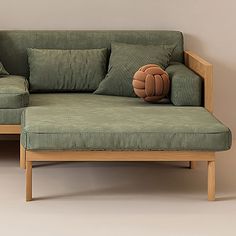 a green couch with two pillows on it and a wooden frame around the armrests