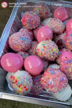 there is a container full of sprinkle covered donuts on the table with pink frosting and sprinkles