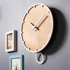 a wooden clock mounted to the side of a wall next to pictures and framed photos