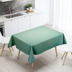 a green table cloth on top of a wooden table in a white kitchen with an oven and dishwasher