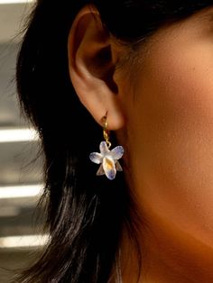 ✦ 18K gold-plated hoops featuring hand-painted ceramic Orchid flowers. ✦ Has about a 1.5" drop. ✦ Nickel and lead-free. ✦ Made with ethically sourced materials in the USA. ✨ Recommended care for gold-plated or brass pieces✨ To prolong the life of your gold-plated pieces, it's recommended to remove your jewelry when doing the following: ✦ swimming (chlorine and salt can affect plating over time), showering, or washing your hands ✦ applying lotions, oils, perfumes, etc. ✦ cleaning, especially with harsh chemicals ✦ when having hair treated Do not use jewelry cleaner on plated items. You can polish this piece with a damp cloth. Ceramic Orchid, Orchid Earrings, Silk Orchids, Accessorize Bags, Orchid Flowers, Book Clothes, Earth Angel, Bandana Hairstyles, Jewelry Pins