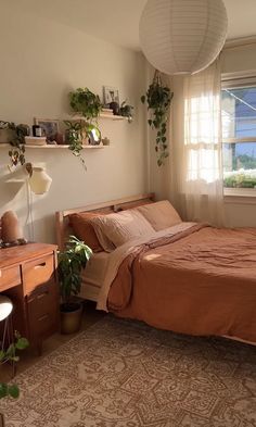 a bedroom with a bed, desk and plants in it's windowsills