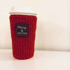 a red knitted coffee cup cozying with a white lid and plastic sip top