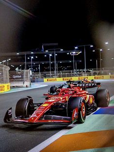 two red race cars driving on a track at night