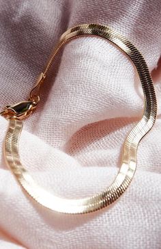 a close up of a gold necklace on a white cloth