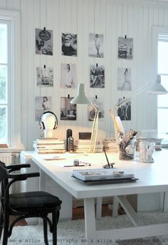 a white desk topped with a laptop computer next to a window covered in lots of pictures