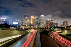 the city skyline is lit up at night with lights streaking down from its skyscrapers